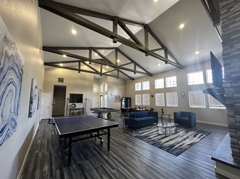 a spacious community clubhouse with a ping pong table and couches